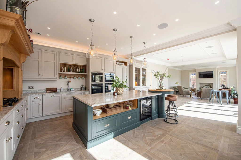 A complete painted kitchen with a central island, fireplace and adjoining living space, designed and made by Corinthian