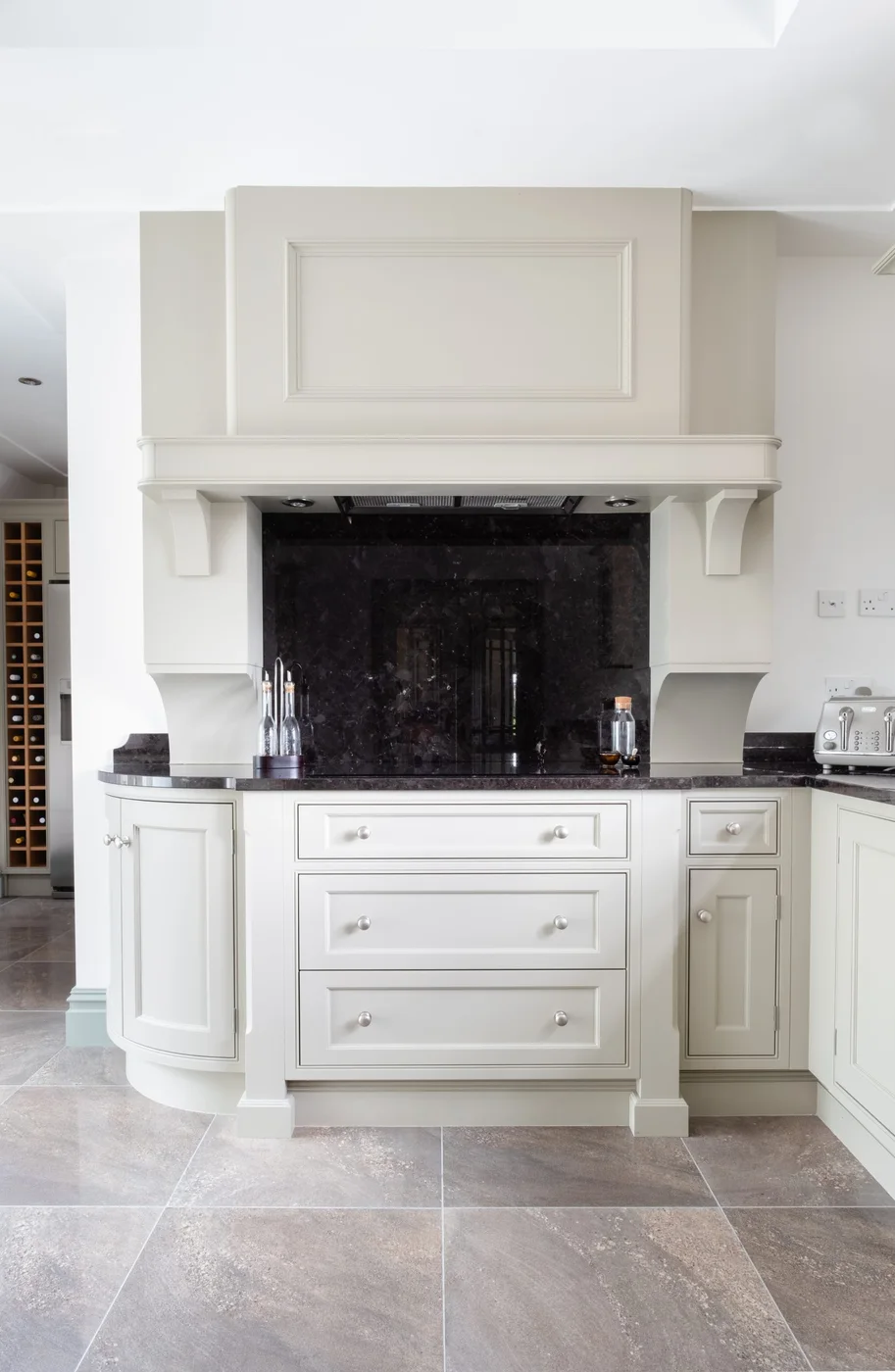 Painted kitchen cabinetry framing a dark stone range